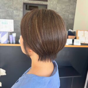 Back of a persons head with short brown hair wearing a light blue shirt indoors in a professional setting