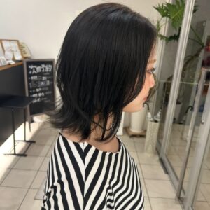 Side profile of a woman with shoulder length layered black hair wearing a black and white striped top inside a modern salon