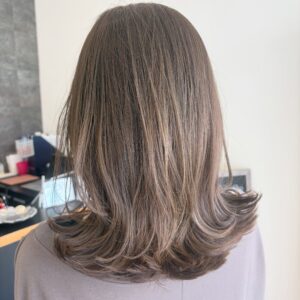 Back view of a person with straight shoulder length brown hair in a salon setting